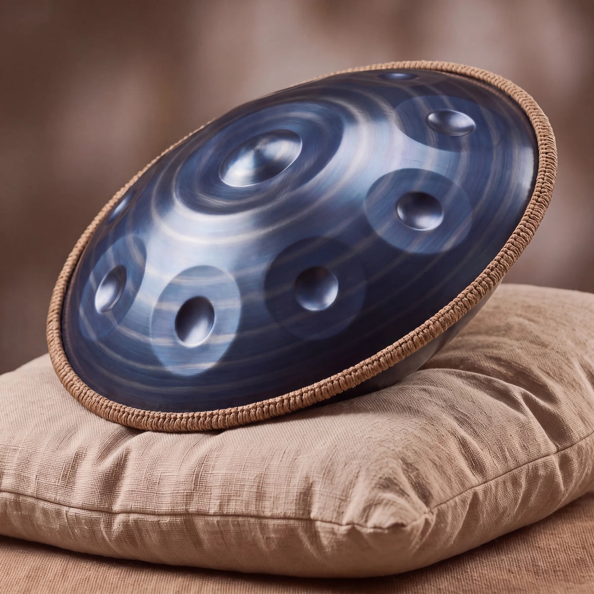Handpan D Kurd 12 notes Nautile Bleu Kovapan – posé de profil sur coussin lin fond bokeh