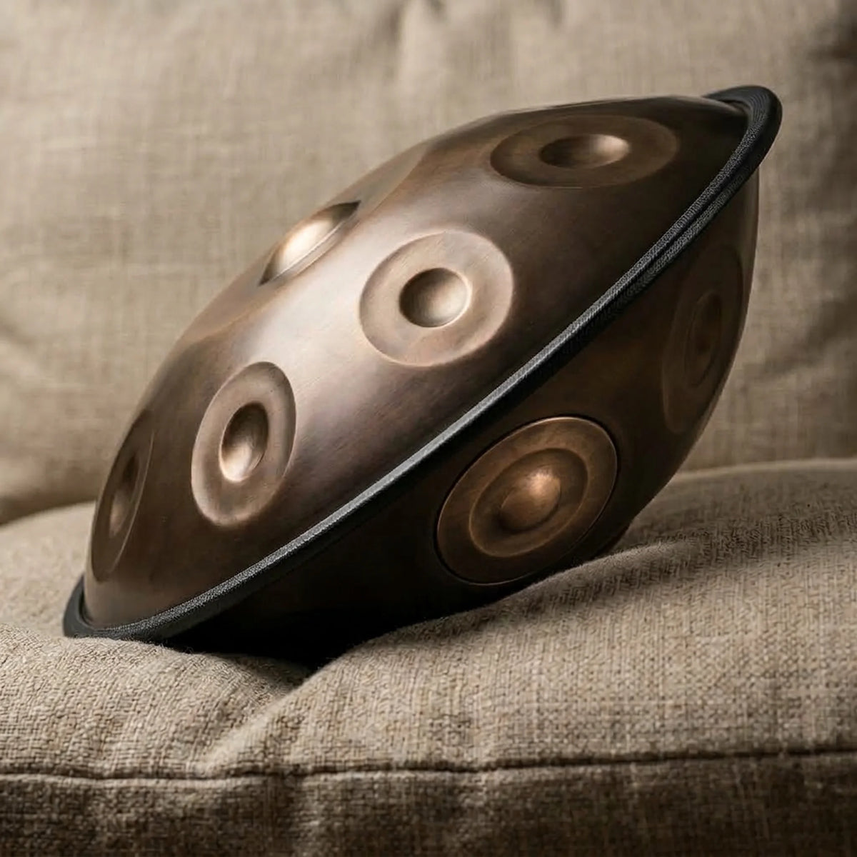 Handpan F Low Pygmy Kovapan – posé de profil sur canapé en lin vue diagonale