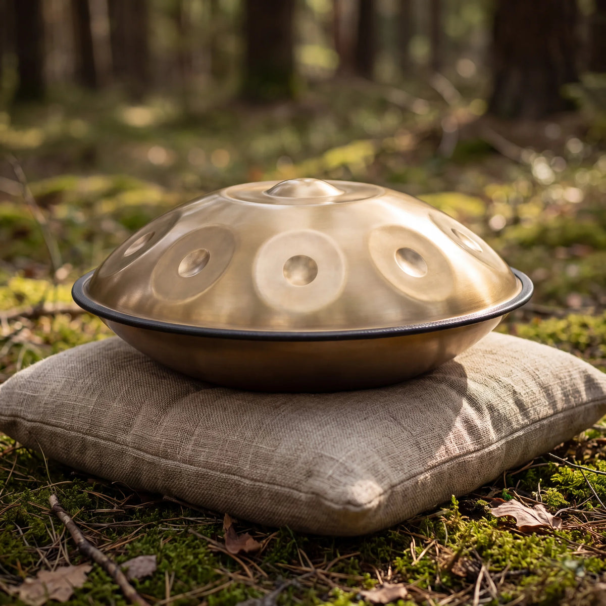 Handpan SAFRAN doré posé sur un coussin en lin, en forêt – Kovapan
