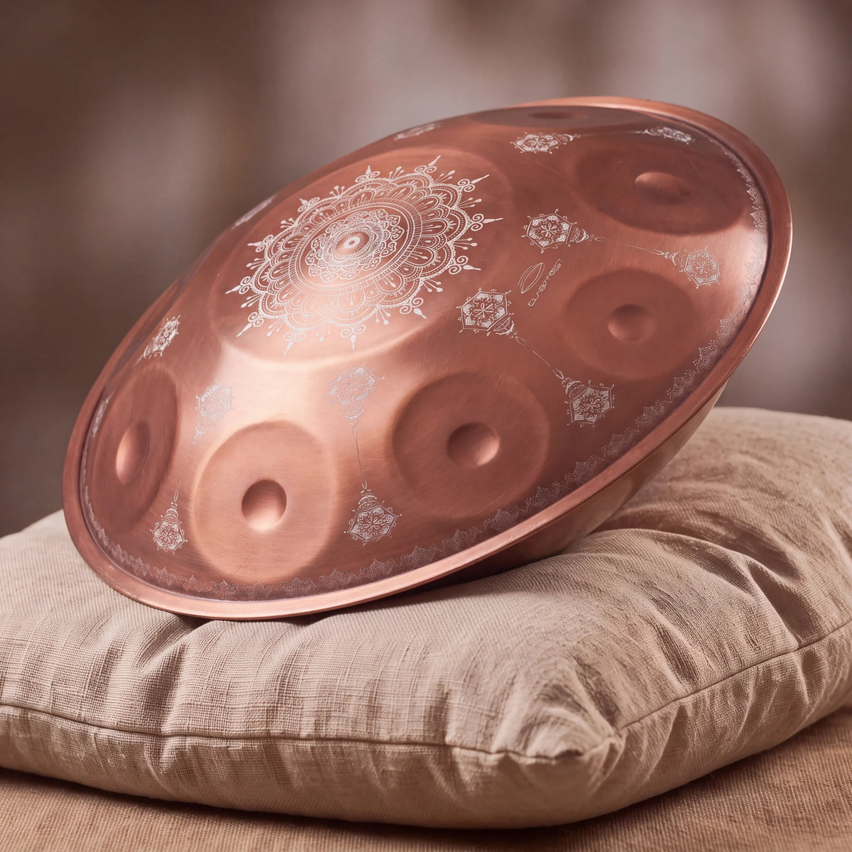 Handpan ROSALIE en Sol Amara, teinte cuivrée rosée, posé de profil sur un coussin – Kovapan