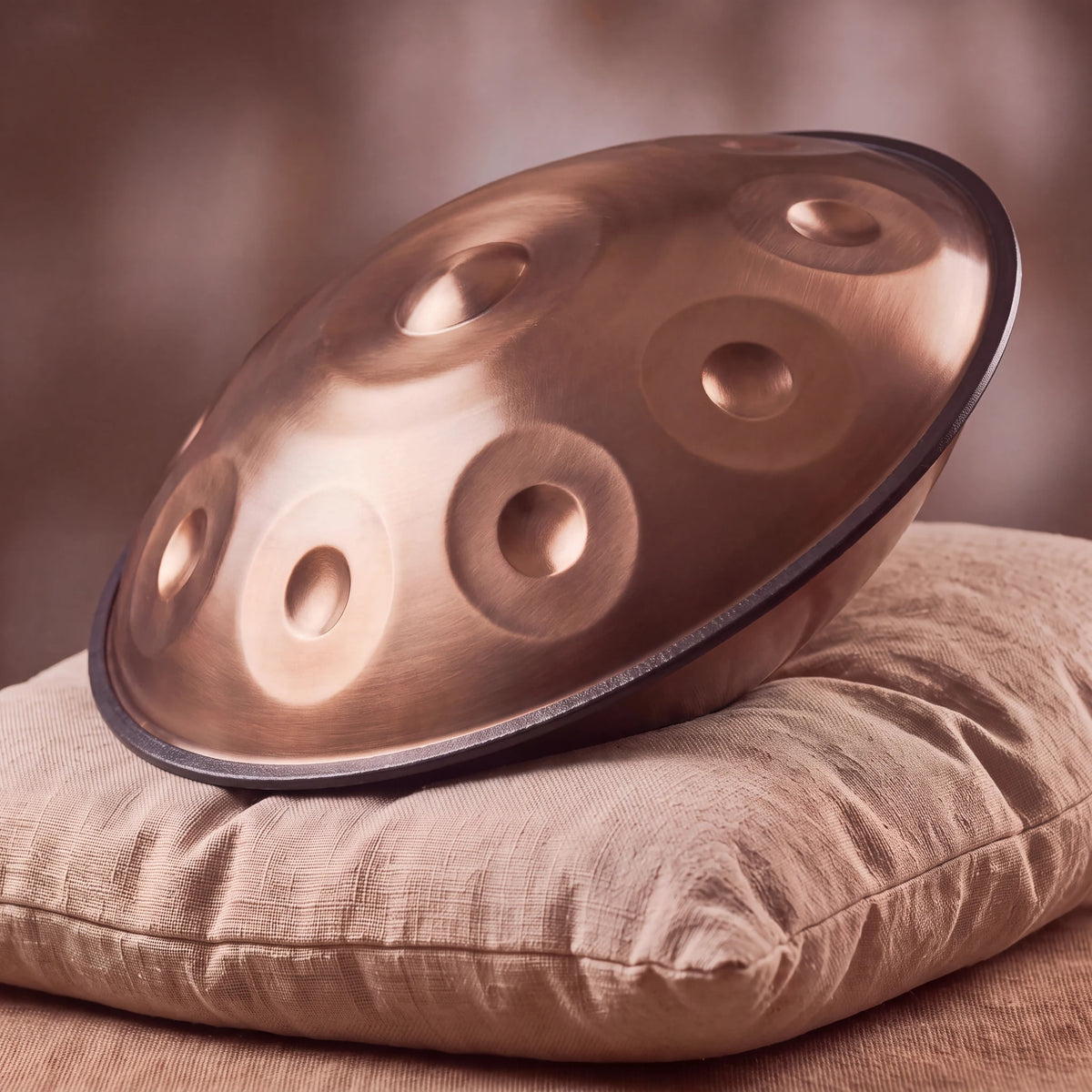 Handpan percussion D Kurd bronze poli – posé sur un coussin de lin naturel, lumière chaude – Kovapan