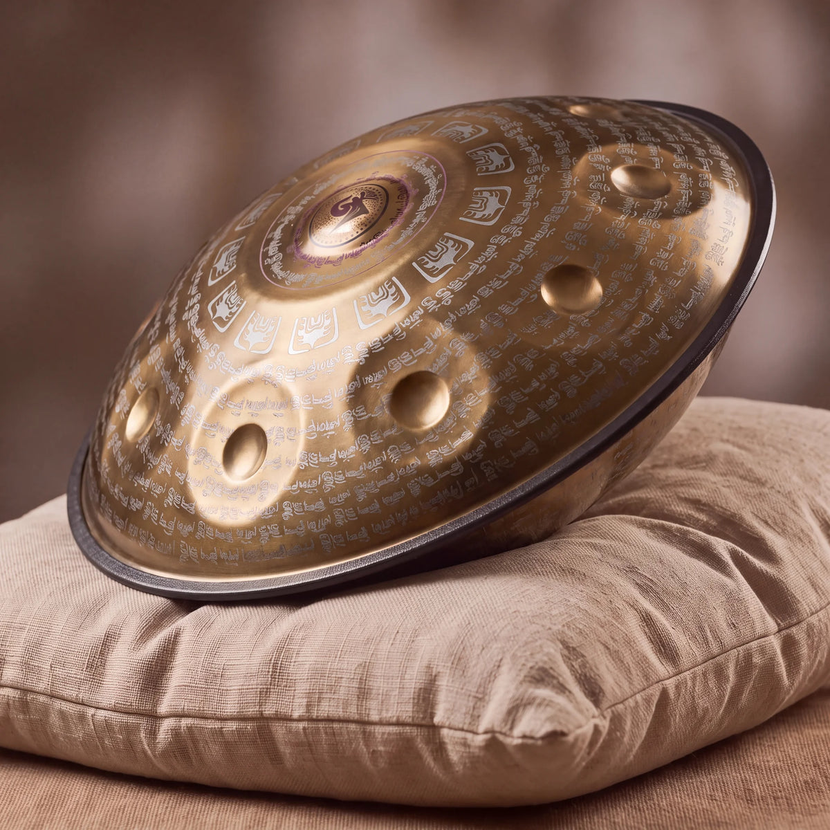 Handpan TALISMAN doré posé de profil sur un coussin en lin – Kovapan
