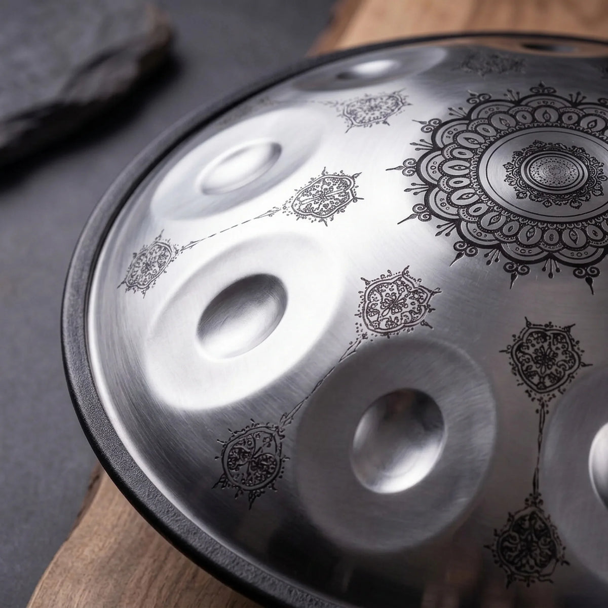 Handpan Celtic Minor Lumandala acier, gros plan des motifs mandala henné et des champs de notes, sur bois et ardoise – Kovapan