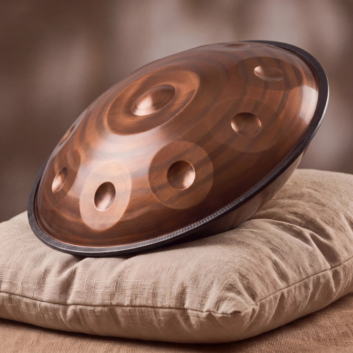 Handpan D Kurd 12 notes Nautile Bronze Kovapan – posé de profil sur coussin lin fond bokeh