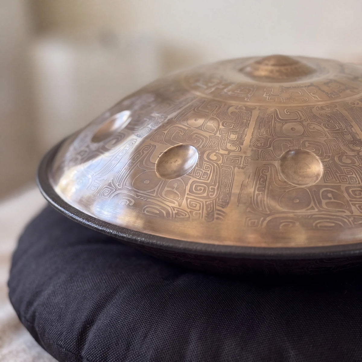Détail des gravures aztèques du handpan NETERO posé sur un coussin noir – Kovapan
