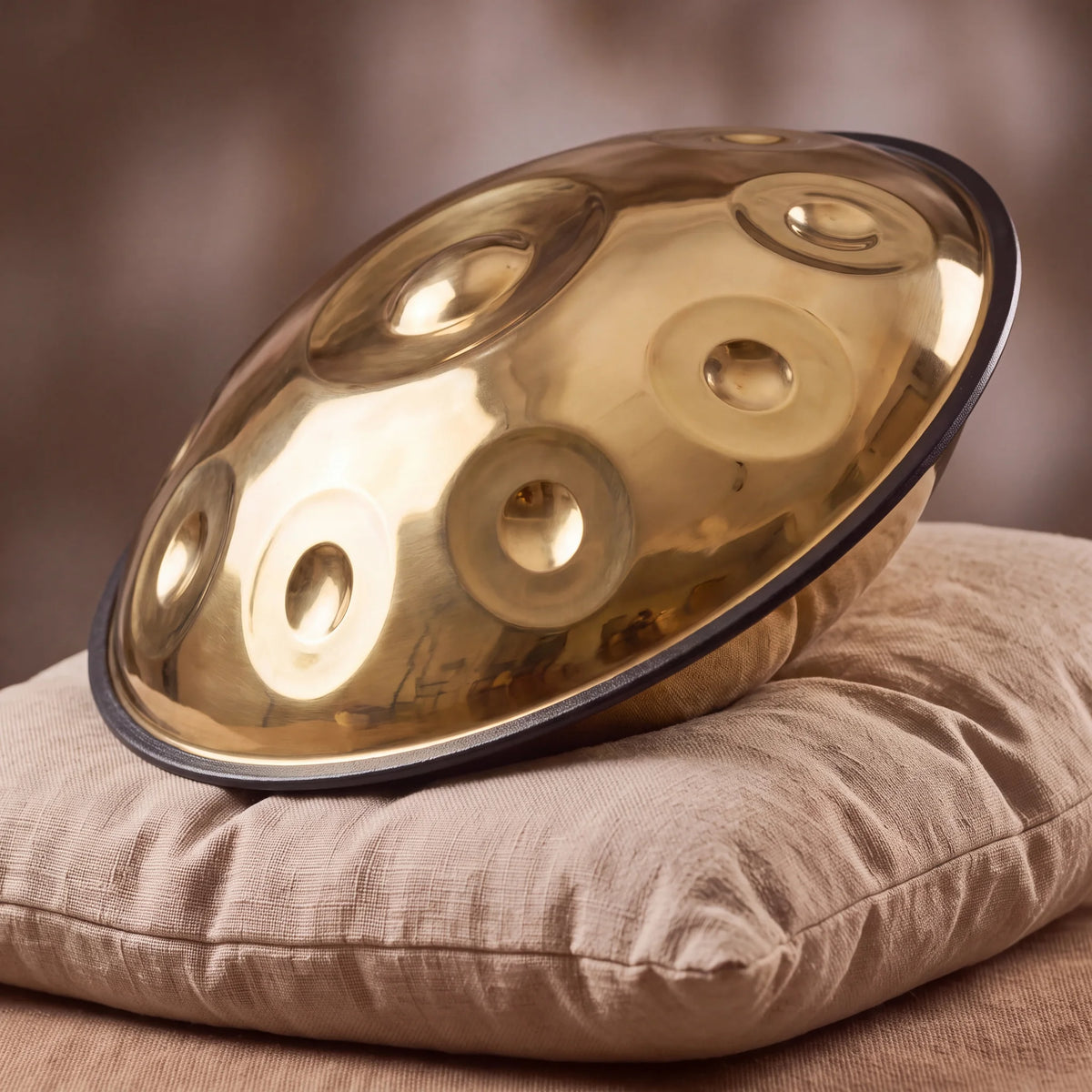Handpan D Kurd 9 notes SOLAS Kovapan doré poli – posé de profil sur coussin lin ambiance chaleureuse