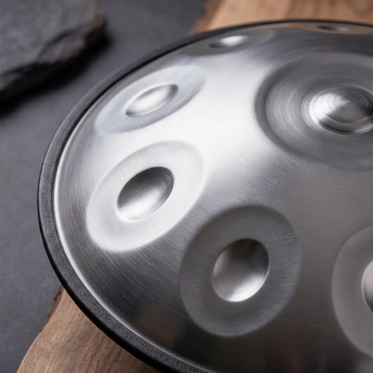 Gros plan sur les champs de notes du handpan STELLAR en acier brossé, sur bois et ardoise – Kovapan