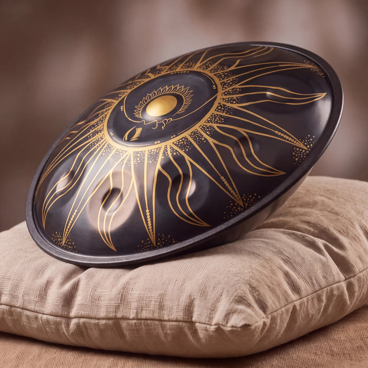 Handpan D Kurd Eclipse noir Kovapan gravures dorées – posé de profil sur coussin lin fond bokeh