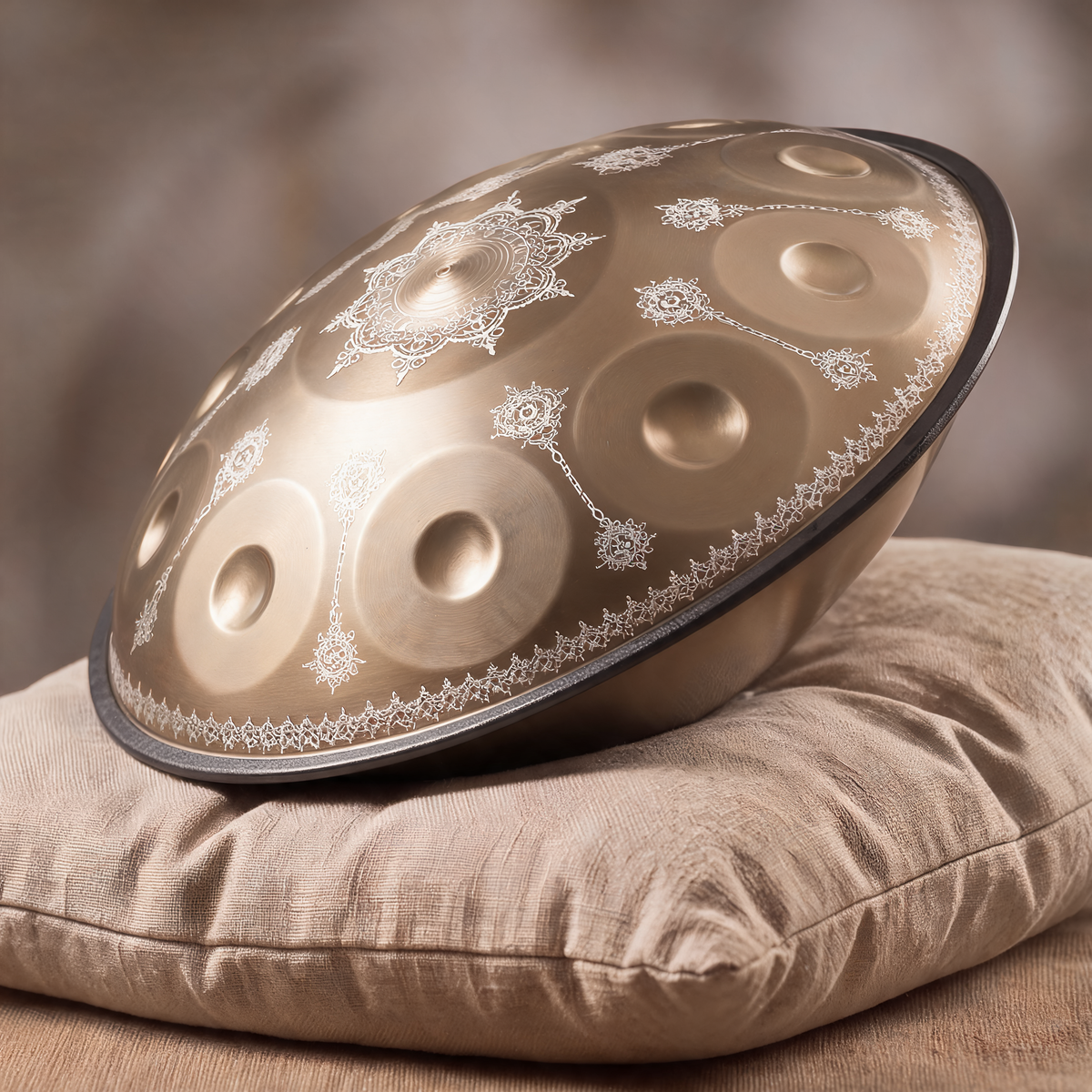 Handpan ARABESQUE finition dorée posé de profil sur un coussin en lin – Kovapan