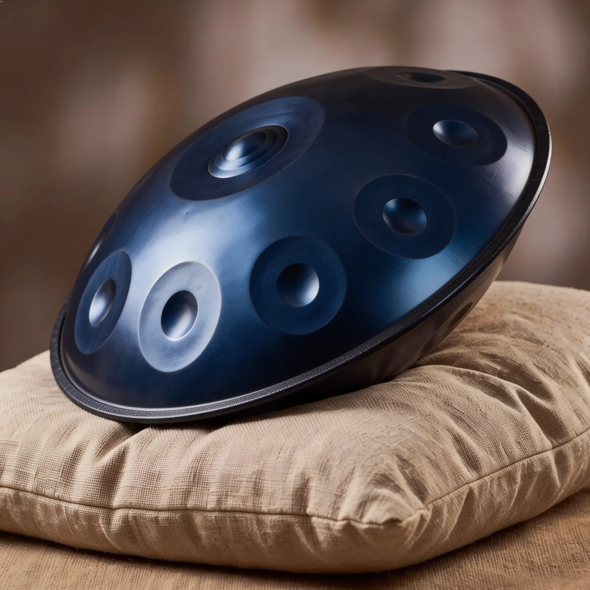 Handpan Equinox D Kurd Kovapan bleu nuit mat – posé de profil sur coussin lin fond bokeh