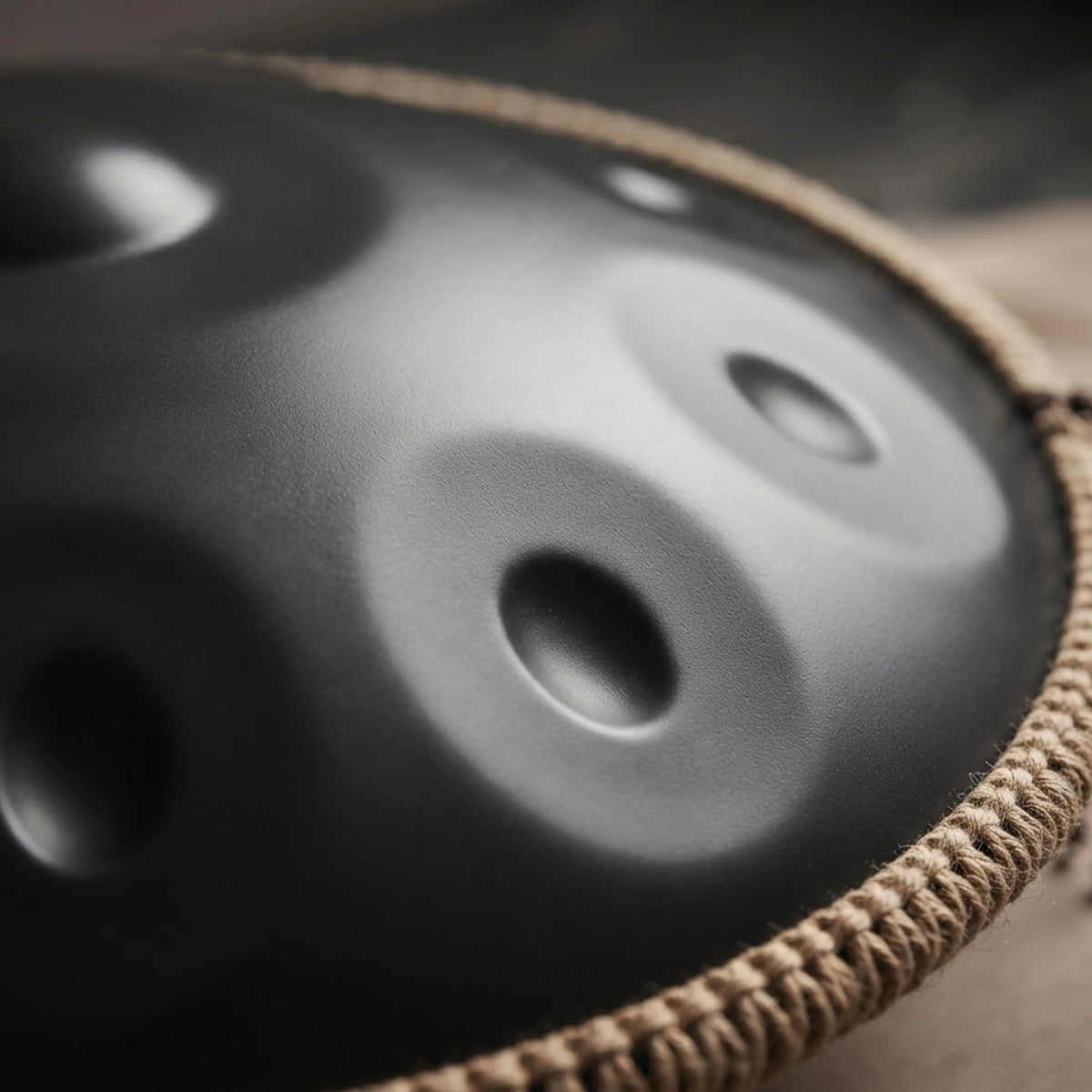 Handpan G minor noir mat bord tressé – détail macro champs de notes surface sombre – Kovapan