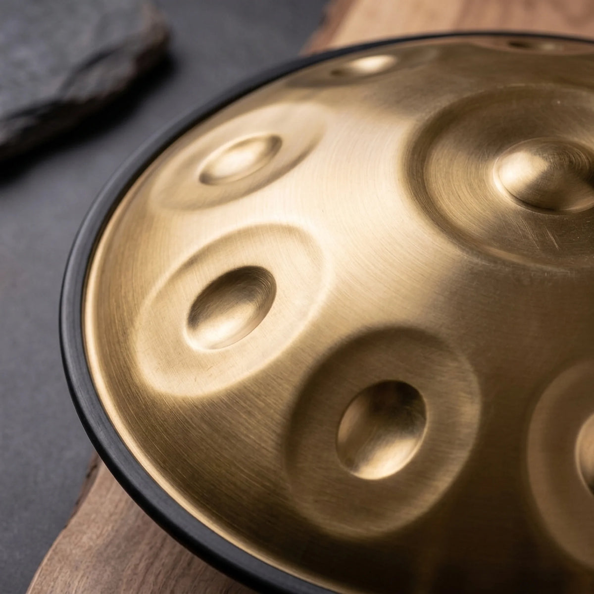 Gros plan sur les champs de notes du handpan SAFRAN doré brossé, sur bois et ardoise – Kovapan