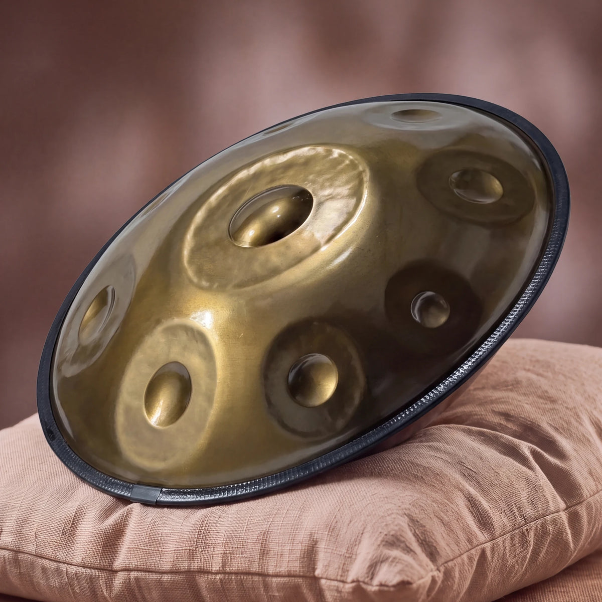 Handpan SIROCCO en Do Hijaz, finition or, posé incliné sur un coussin en lin rose poudré – Kovapan