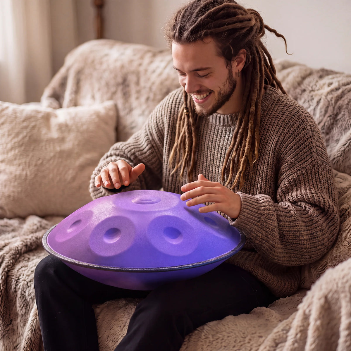 Musicien jouant du handpan violet IRIS assis sur un canapé – Kovapan