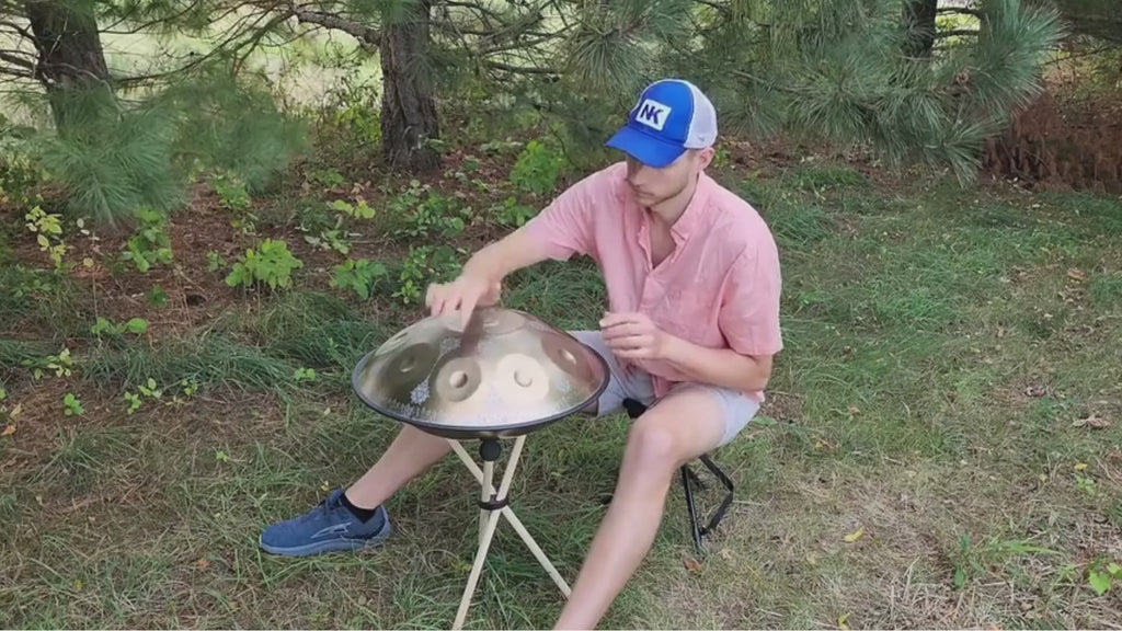 Musicien jouant du handpan oriental ARABESQUE doré sur trépied en plein air, démonstration du son – Kovapan